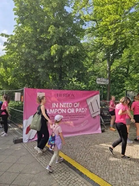 Herbox rosa mensskyddsautomat hänger på en rosa reklamskylt på Women’s race i Berlin