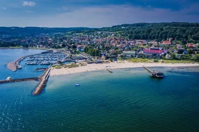 bild på havet och båthamnen i Båstad med stranden och skogen i bakgrunden en solig sommardag