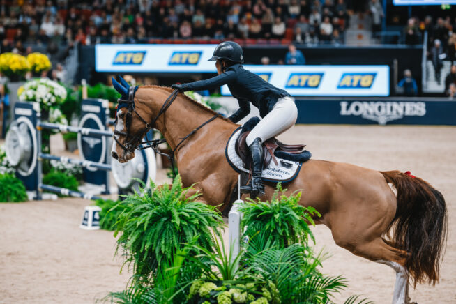 En bild på en kvinna och en brun häst som hoppar över ett hinder på Götenorg Horseshow i Scandinavium.